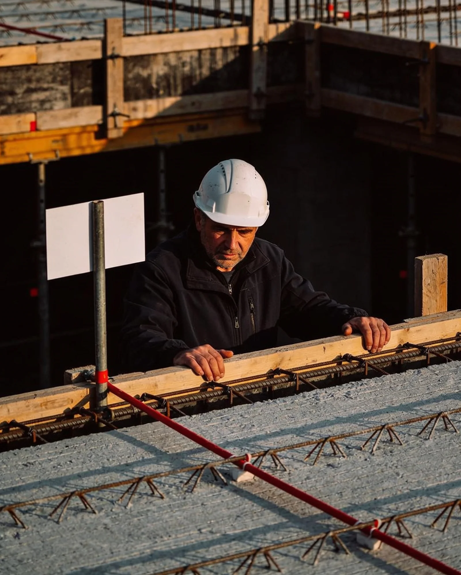 Le chef de chantier, casque sur la tête, vérifie le coffrage d'une dalle à Montreuil
