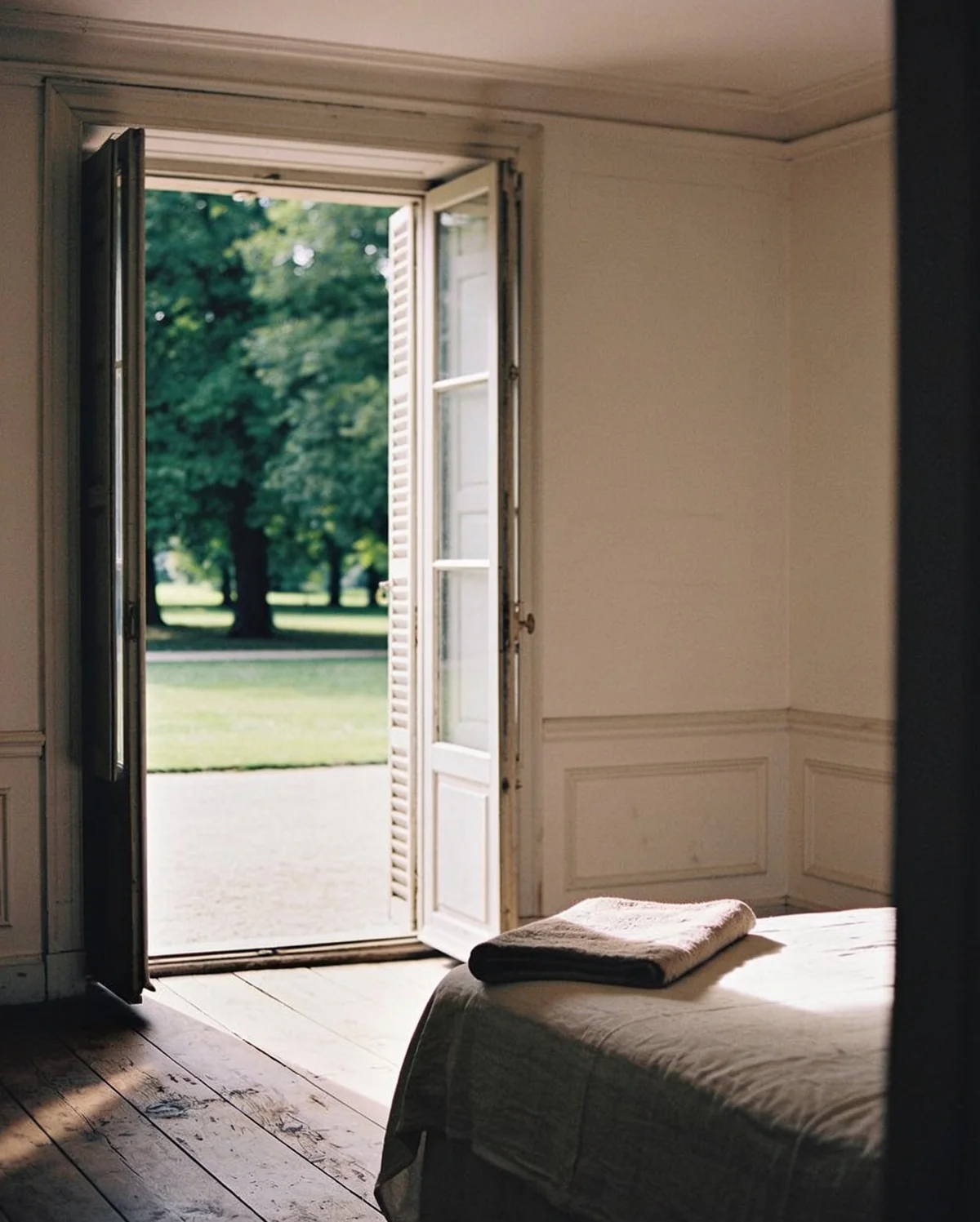 Une chambre aux murs clairs, lit de lin et fenêtre sur le parc